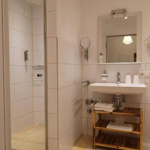 ein Bad mit einer Dusche, einem Waschbecken und einem Spiegel in der Unterkunft Ferienwohnung Gutshof in Seenähe in Dießen am Ammersee