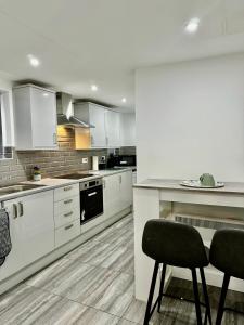 a kitchen with white cabinets and a table and two chairs at Rooms Near Me - Apartment 1, Sky Tv, Free Parking 