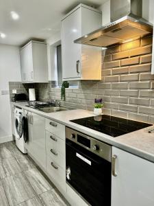 a kitchen with white cabinets and a stove top oven at Rooms Near Me - Apartment 1, Sky Tv, Free Parking 