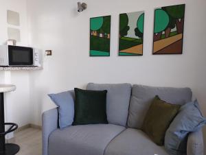 un sofá en una sala de estar con pinturas en la pared en La Casa nel Parco - Stadio Olimpico, Auditorium con posto auto, en Roma