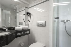 ein Badezimmer mit Dusche, Toilette und Waschbecken in der Unterkunft IntercityHotel Kiel in Kiel