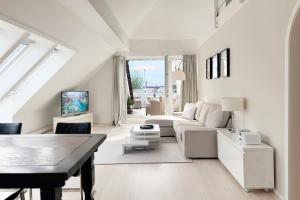 a white living room with a couch and a table at Techts Apartmenthaus in Timmendorfer Strand