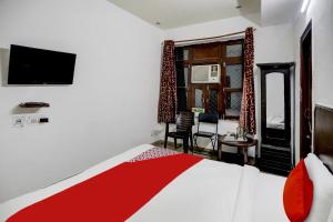 um quarto com uma cama e uma televisão na parede em OYO Flagship Hotel Majestic em Gurgaon