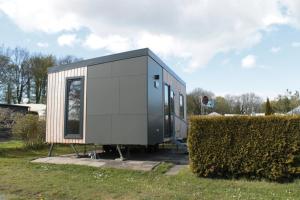 a tiny house sitting next to a hedge at Mobilheim ECO in Borgdorf-Seedorf