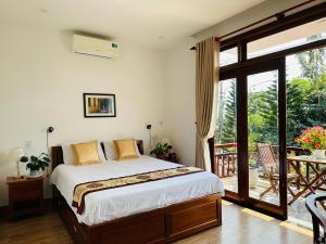 Schlafzimmer mit einem Bett und einer Glasschiebetür in der Unterkunft Thuy House Hoi An in Hoi An