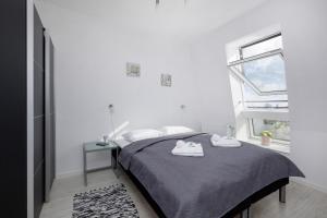 een witte slaapkamer met een bed en een raam bij Apartamenty "Bałtyk" Armii Krajowej w Świnoujściu by Renters in Świnoujście