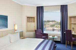 ein Hotelzimmer mit einem Bett und zwei Stühlen und einem Fenster in der Unterkunft IntercityHotel Kiel in Kiel