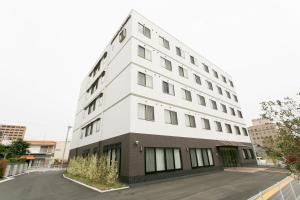 a white building with black windows on a street at Okawa Riverside Hotel in Ōkawa