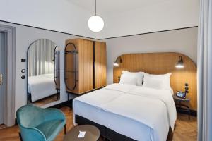 a bedroom with a large white bed and a blue chair at Hotel Astoria Wien in Vienna