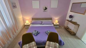 a bedroom with a bed with purple sheets and two chairs at Apartment Milevoj in Koromačno