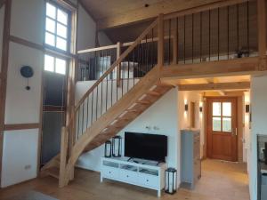een woonkamer met een houten trap en een televisie bij Moarhof Ferienwohnung2 in Dietramszell