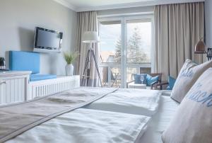 a white bedroom with a large bed and a tv at Hotel Am Medemufer in Otterndorf