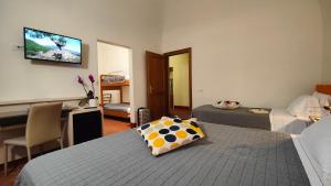 una camera con 2 letti, una scrivania e una TV di Chiostro Delle Monache Hostel Volterra a Volterra