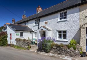 a white house with a stone wall at Syms Cottage Cutcombe in Cutcombe