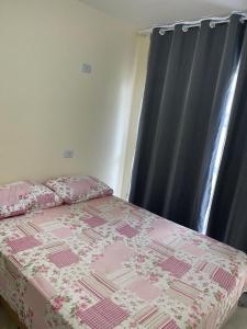 a bedroom with a bed with a pink quilt and a window at Casa 3 Quartos, 2 suites, piscina e sossego in São José da Coroa Grande