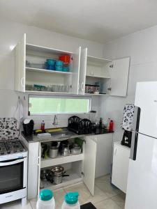 een keuken met witte kasten, een wastafel en een koelkast bij Casa 3 Quartos, 2 suites, piscina e sossego in São José da Coroa Grande