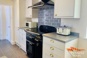 a kitchen with a black stove and white cabinets at The West Wing, Featherstone in Coanwood