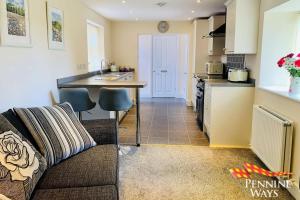 a living room with a couch and a kitchen at The West Wing, Featherstone in Coanwood