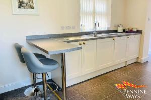a kitchen with a counter and a sink and a stool at The West Wing, Featherstone in Coanwood