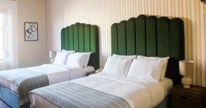 2 bedden in een hotelkamer met groene hoofdeinden bij The Columbia in Londen