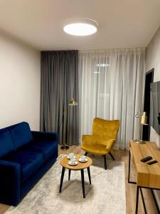 a living room with a blue couch and a yellow chair at Apartos Seaside Garden Luxury Apartments in Świnoujście