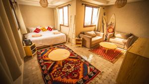 a bedroom with a bed and a couch and a table at The Moroccan Surf House in Imsouane