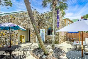 a patio with tables and umbrellas in front of a building at Sunshine Cottage 31C By Pkrm in Pensacola