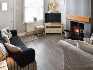 a living room with a couch and a fireplace at Fuchsia Cottage in Sea Palling