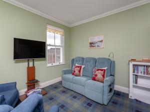 a living room with a couch and a flat screen tv at The Old School House Annex in Tain