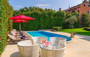 a pool with chairs and a table with a red umbrella at Villa Duga in Poreč