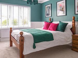 a bedroom with a bed with green and pink pillows at Cranny Hill in Walpole