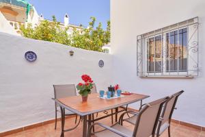une table en bois avec des chaises et un vase avec des fleurs. dans l'établissement Apartamento Almijara 2, à Nerja