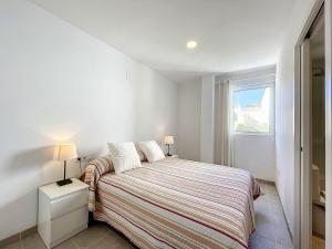 a white bedroom with a bed and a window at Roca Fornells, Atico Maritimo F05 in Fornells