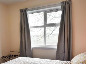 a bedroom with a window with curtains and a bed at Mains Of Asloun Two - Uk44788 in Alford