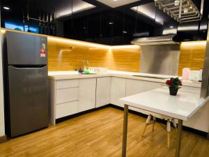 uma cozinha com um frigorífico de aço inoxidável e uma mesa em Eshue Designer Suites @ Simfoni Towers em Cheras