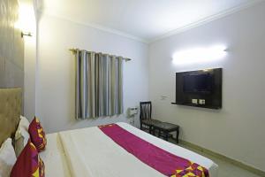 a bedroom with a bed and a tv on the wall at Airport KINGDOM in New Delhi