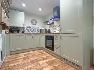a kitchen with white cabinets and a wooden floor at Lyndene Cottage in Moel-tryfan