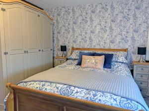 a bedroom with a bed with blue and white bedding at Lyndene Cottage in Moel-tryfan