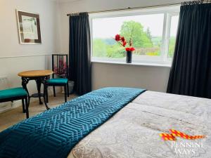 a bedroom with a bed and a window and a table at The Spotty - Homely Stay in a Former Inn in Haltwhistle