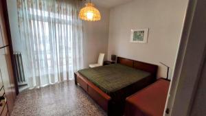 een slaapkamer met een bed en een raam met een kroonluchter bij Casa Riverbero in Novara