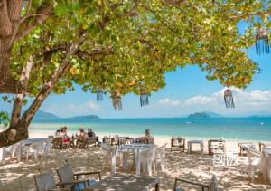 personas sentadas en la playa bajo un árbol en Nitiporn Resort kohphayam & seaagain bar and restaurants, en Ko Phayam