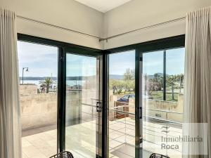 een kamer met glazen schuifdeuren en uitzicht op de oceaan bij Adosado con piscina y vistas al mar in Fornells