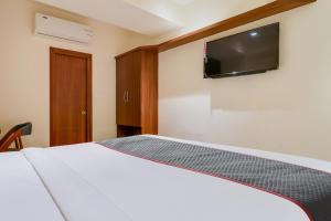 a bedroom with a bed with a tv on the wall at Super Townhouse 1144 Hotel RCC 7 Lamps in Alipur