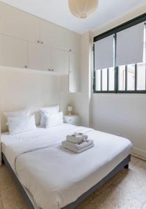 a white bedroom with a large bed with towels on it at Chemin Vert/Voltaire : Charming Apartment 4P in Paris