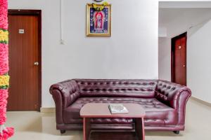 a brown leather couch in a living room with a table at Capital O New Paradise Inn in Irugūr