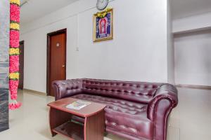 um sofá de couro castanho num quarto com uma mesa em Capital O New Paradise Inn em Irugūr