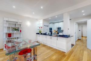 a kitchen with white cabinets and a glass counter at Beautiful 2Bed Apartment with lift in Kensington in London