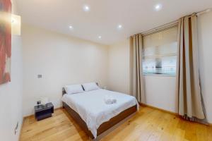 a white bedroom with a bed and a window at Beautiful 2Bed Apartment with lift in Kensington in London
