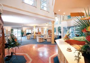 a large lobby with tables and potted plants at Ailwaldhof Parkhotel & Spa in Baiersbronn
