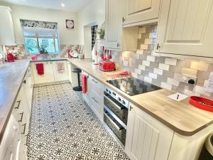 a kitchen with white cabinets and a tile floor at Sea View Three Bed Detached Home - With Parking - Next to Beach! in Bournemouth